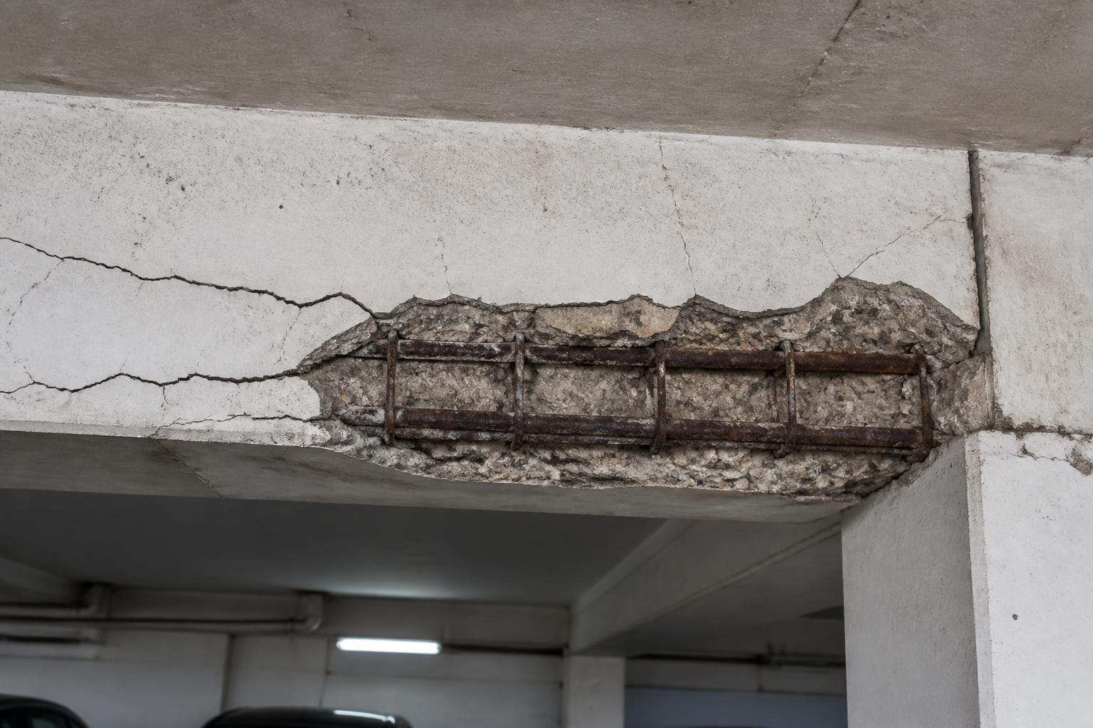 Viga de concreto armado com armadura aparente, corrosão e concreto desplacando em garagem de condomínio em Ribeirão Preto